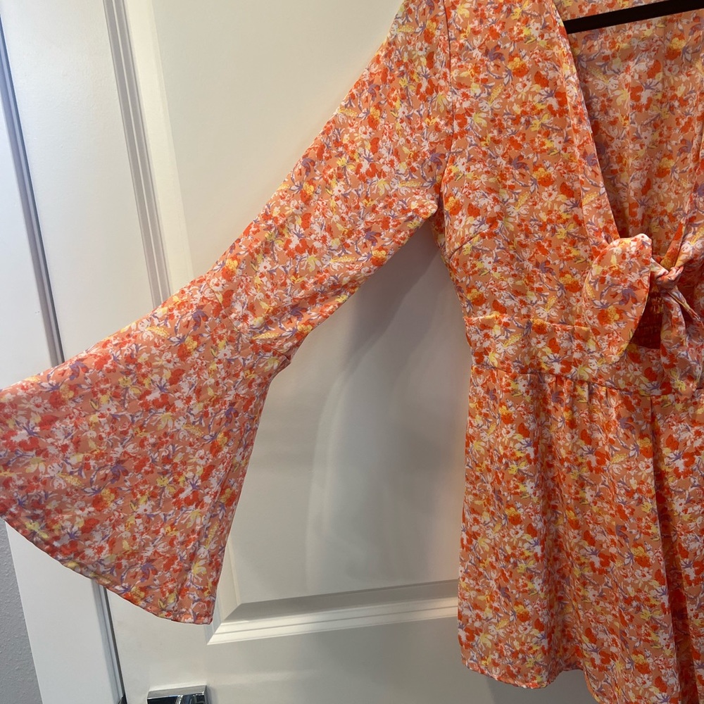 Pink Lily floral tie-front romper. Bell sleeves and flowy shorts hem.